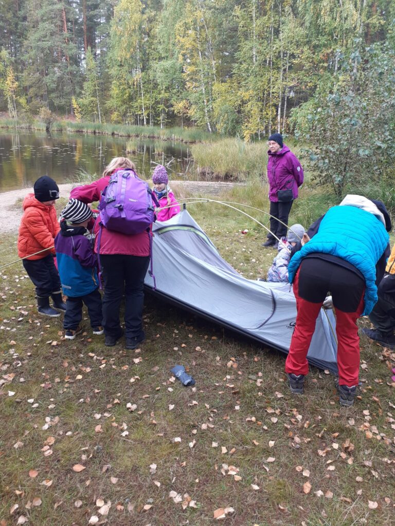 Aikuisia ja lapsia kokoamassa telttaa.
